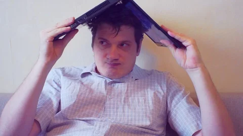 Scared crazy user sitting with laptop on head Stock Footage 86165976