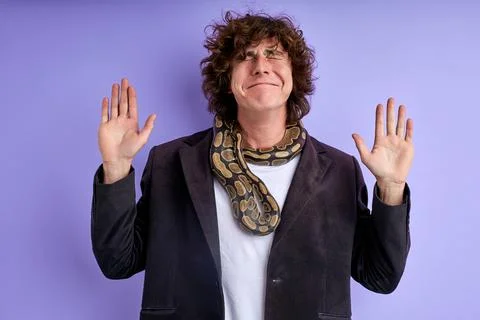 Scared curly guy stand with spread arms frightened by python 스톡 사진