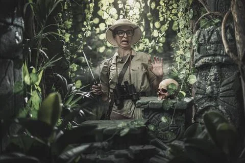 Scared explorer finding a skull in the jungle Stock Photos