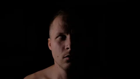 Scared face of a man in the dark. Only half of the face is highlighted. Stock Footage 94971192