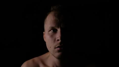 Scared face of a man in the dark. Only half of the face is highlighted. Stock Photos