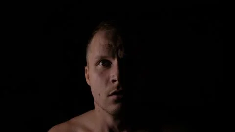 Scared face of a man in the dark. Only half of the face is highlighted. Stock Photos