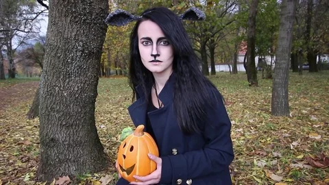 Scared girl in helloween costume and pumpink lamp looking at the camera Stock Footage 80831766