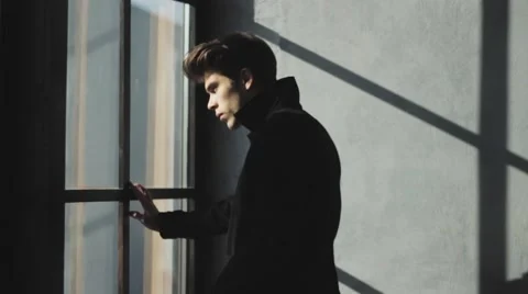 Scared man in black jacket walk to window to look at something Stock Footage 60961236