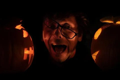 Scared man in glasses between two halloween pumpkins. Halloween concept 스톡 사진