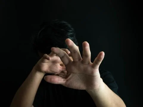 Scared man put his hands forward. Man with emotion of fear isolated on black Stock Photos