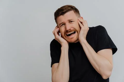 Scared man screaming while being afraid and looking with frightened expression Stock Photos