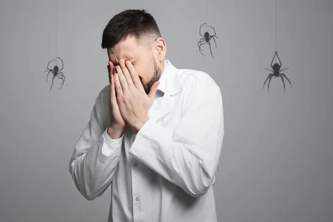 Scared man suffering from panic attack on grey background. Shadows of spide.. Foto stock