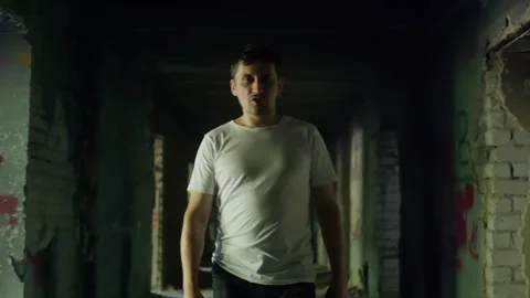 Scared man walking in dark corridor of abandoned building Stock Footage 304516786