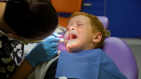 Scared red-haired boy crying at reception at dentist in dental chair. Pediatric Stock Footage 123314917