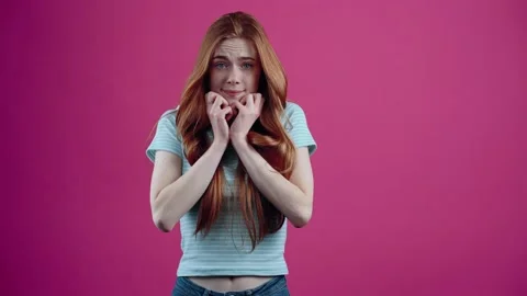 The scared redhead covers her face with her hands and then leans back scared Stock Footage 152535324
