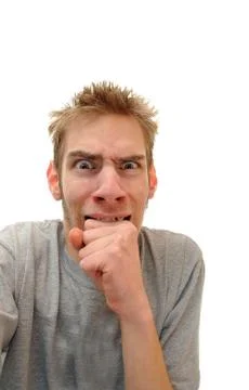 Scared terrorized young man bites down on his hand on the verge of tears. iso Stock Photos