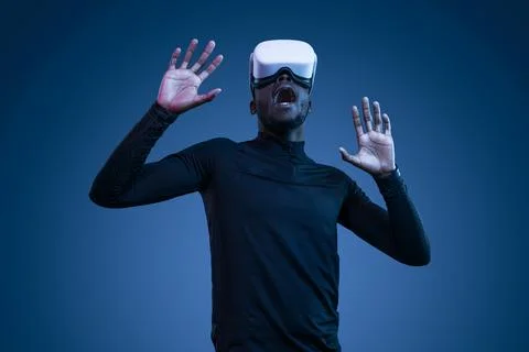 Scared young black guy yelling while exploring virtual reality in modern headset Stock Photos