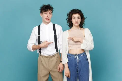 Scared young couple pointing at each other with index fingers, having frighten Stock-Fotos