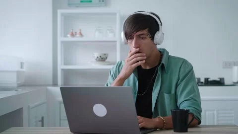 Scared young man in headphones getting bad results on computer at home office Stock Footage 190935413
