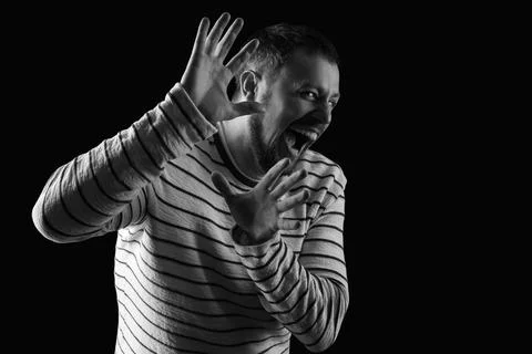 Scared young man screaming on black background Stock Photos