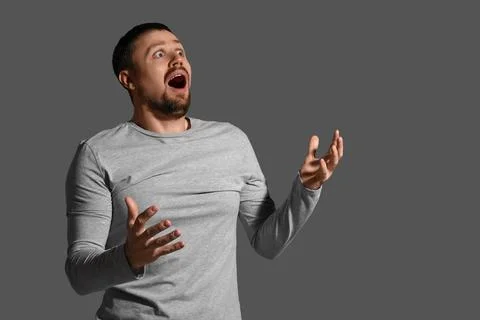 Scared young man screaming on dark background Stock Photos
