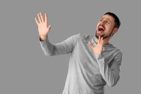 Scared young man screaming on grey background Stock Photos