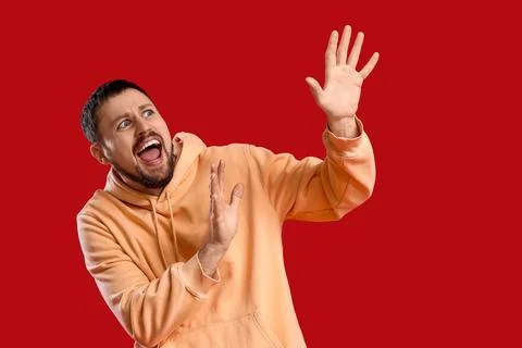Scared young man screaming on red background Stock Photos