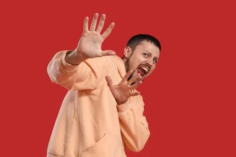 Scared young man screaming on red background Stock Photos
