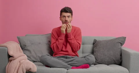 Scared young man watches horror film with special effects reacts on scary scene Stock Footage 143631412