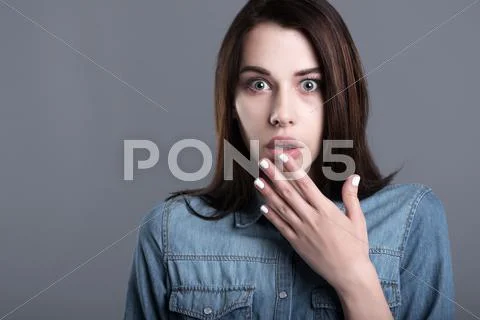 Scared young woman raising hand to her mouth Stock Photos