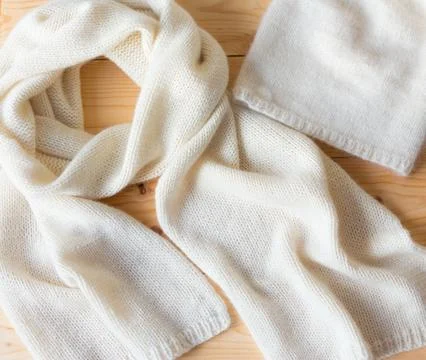 Scarf and hat beige manually linked from a soft fluffy wool on wooden backgro Stock Photos