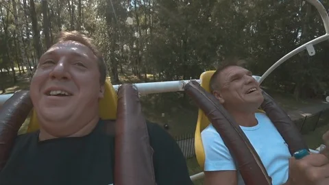 Scary carousel. Two men. Upside down. On the swing. Close-up. Slow motion Stock Footage 94197482