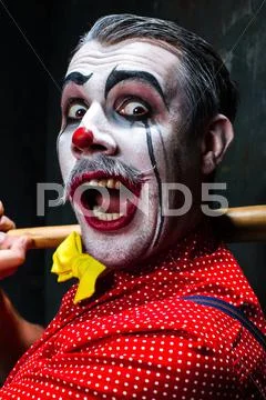 The scary clown and baseball-bat on dack background. Halloween concept Stock Photos