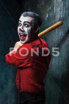 The scary clown and baseball-bat on dack background. Halloween concept Stock Photos