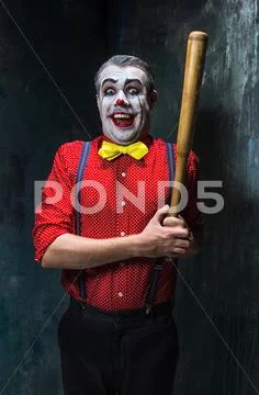 The scary clown and baseball-bat on dack background. Halloween concept Stock Photos