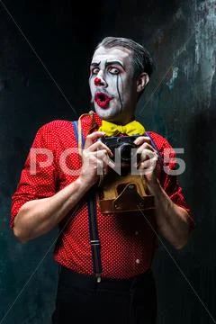 The scary clown and a camera on dack background. Halloween concept Stock Photos
