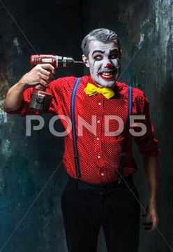 The scary clown and electric drill on dack background. Halloween concept Stock Photos