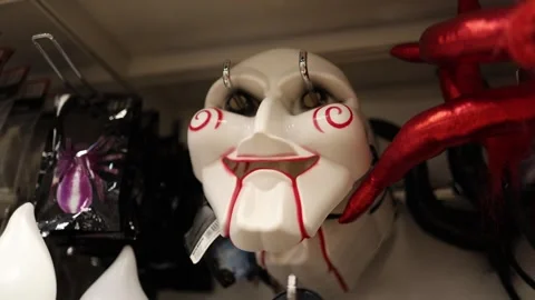 Scary devil mask with red horns hangs among Halloween costume accessories 動画素材 342914498