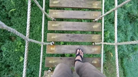 Scary, dizzy point of view (POV) shot of man walking across shaky wooden rope br Stock Footage 151304669