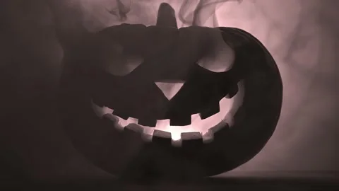 Scary glowing pumpkin Jack-o-lantern in the smoke on a dark background. Stock Footage 137962093