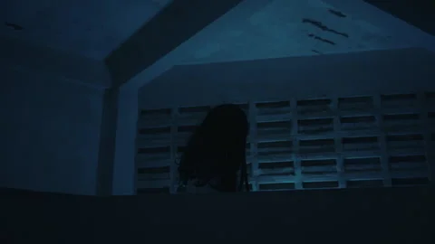 Scary halloween ghost with long black hair emerging from deep shadows creates Stock Footage 343827475