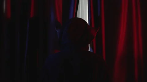 Scary man with pig mask looking behind curtains in red room Stock Footage 233084734