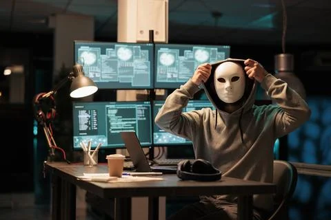 Scary masked hacker installing virus to hack system Foto stock