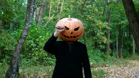 Scary pumpkin-headed man. Pulls a knife out of his eye and chases after someone. Stock Footage 116493689