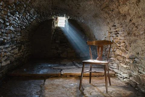 Scary underground, old dark cellar with an old abandoned chair Foto stock