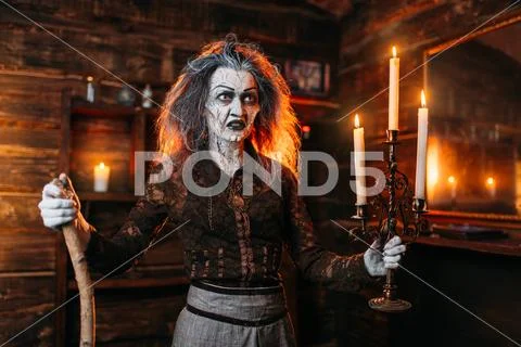 Scary witch with candlestick and cane reads spell Stock Image #103932486