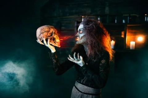 Scary witch holds human skull and reads the spell Foto stock