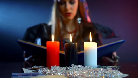 Scary young witch holding devil book and reading spell in dark room among Stock Footage 121967380