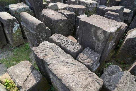 Scattered ancient stone blocks and ruins at an archaeological temple site. Stock Photos