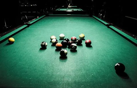 Scattered billiard balls on pool table in dim bar 库存照片
