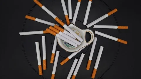 Scattered cigarettes spin on a black background Stock Footage 120175897