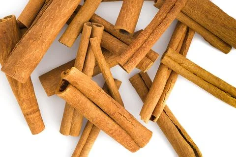 Scattered cinnamon bark segments on white, showcasing their coarse texture .. Stock Photos