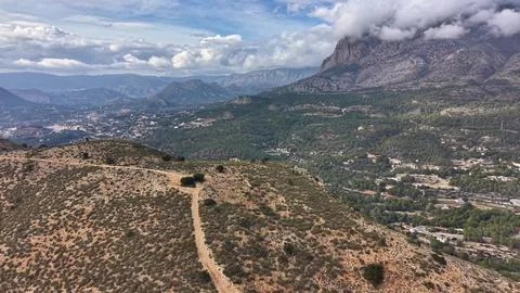Scattered clouds over distant mountain vista. Dusty trail guides towards mo.. Foto stock