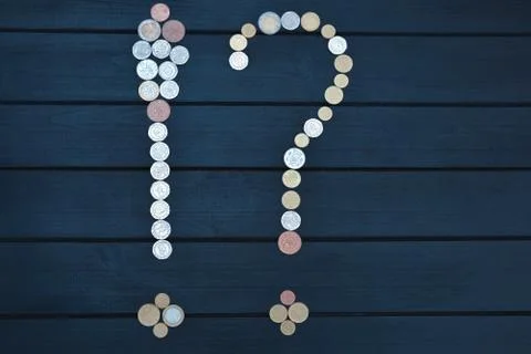 Scattered coins of different countries in the form of a question mark and an  Stock Photos